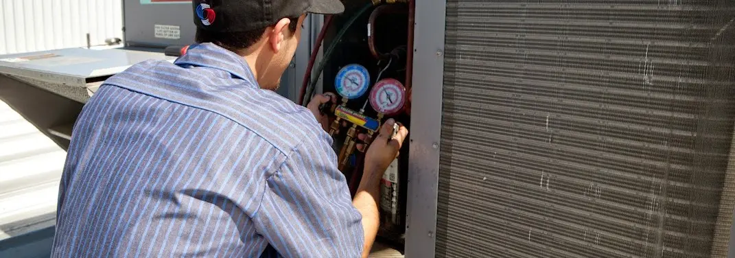 HVAC technician servicing a condenser unit in Hermiston